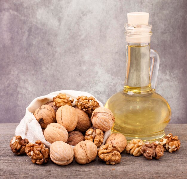 Photo glass jug with walnut oil and walnuts in a woven bag