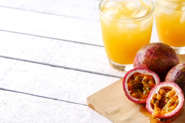 A glass of juice and fresh passion fruit on wooden table. copy space