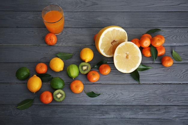 Glass of juice, halves of pomelo and fresh citrus fruits on wooden table