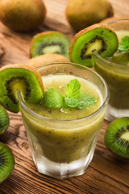Glass of kiwi juice with fresh fruits on wooden table