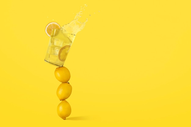 Glass of lemonade is on top of lemons in balance and is about to fall