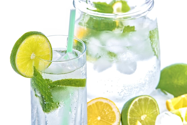 A glass of lemonade with limes and limes on the side