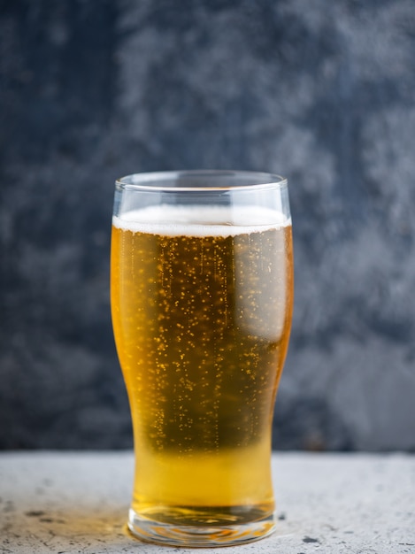 A glass of light beer on a dark background