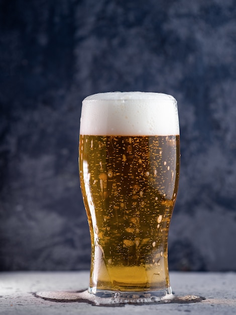 A glass of light beer on a dark background