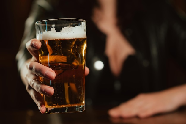 Glass of light beer lager with foam in the hand of a woman