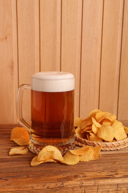 Glass of light beer and potato chips on a wooden table