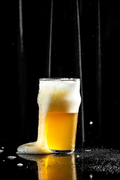 Glass of light beer with a thick foam beer splash black background vertical image place for text