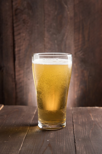 Glass of light beer on wooden table.