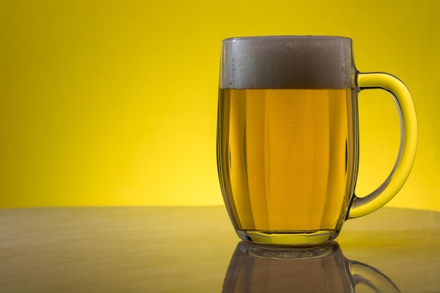 Foto un bicchiere di birra leggera su uno sfondo giallo