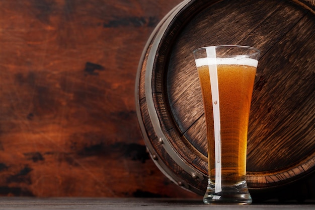 Стакан светлого пива и старая деревянная бочка с копировальным пространством
