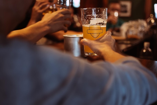 Glass of light unfiltered wheat beer in hand of man in pub behind the bar