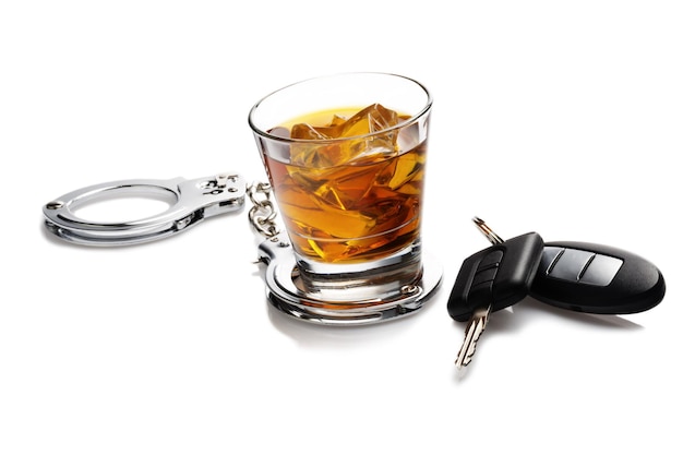 glass of liquor with car keys and handcuffs