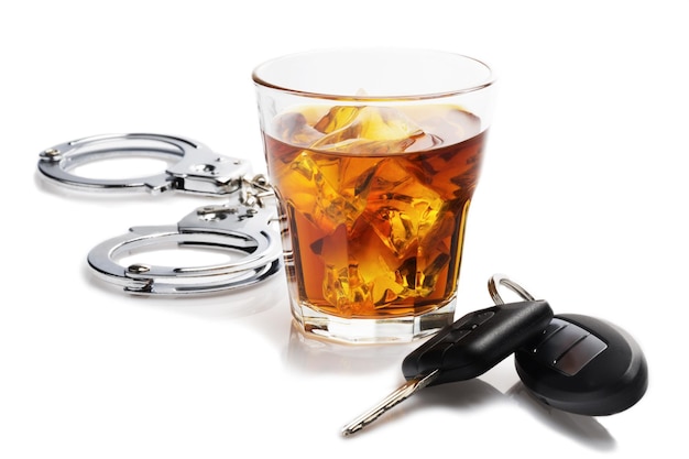 glass of liquor with car keys and handcuffs