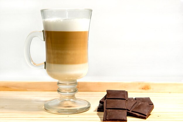 Glass of macchiato latte with dark chocolate.