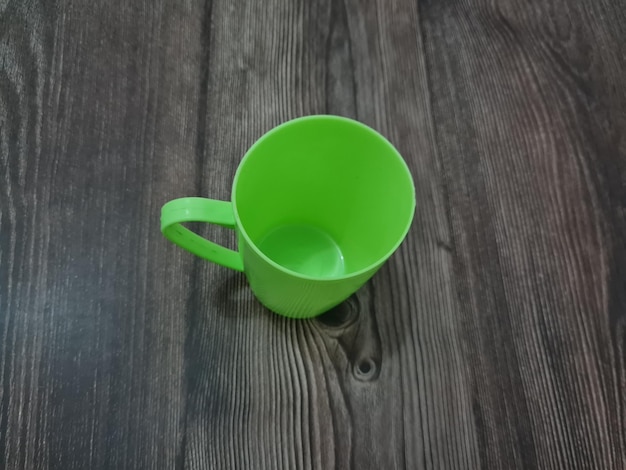 A glass made of plastic with a green handle