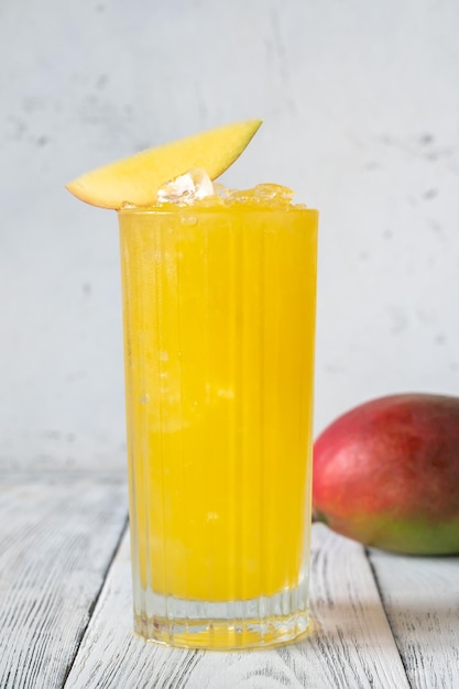 Glass of Mango Punch cocktail garnished with mango slice