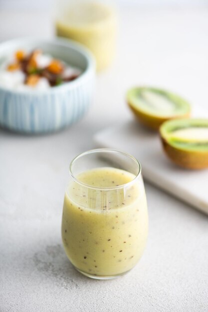 Photo a glass of mango smoothie with kiwi fruit in the background.