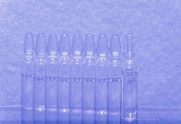 Glass medical ampoule vial for injection medicine is liquid sodium chloride with of aqueous solution in ampulla close up bottles ampule multicolor