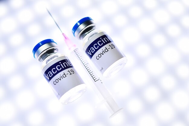 A glass medical jar with the covid-19 coronavirus vaccine on an LED background. Vaccination against coronavirus infection.