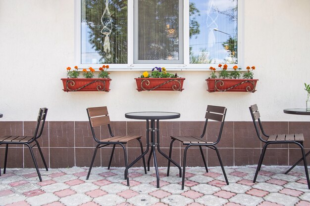 Glass and metal tables and chairs on a summer terrace cafe by the window