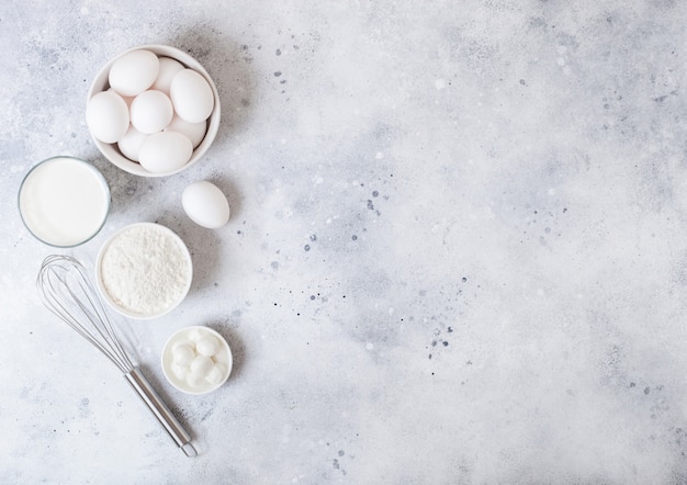 Glass of milk, bowl of flour and eggs.