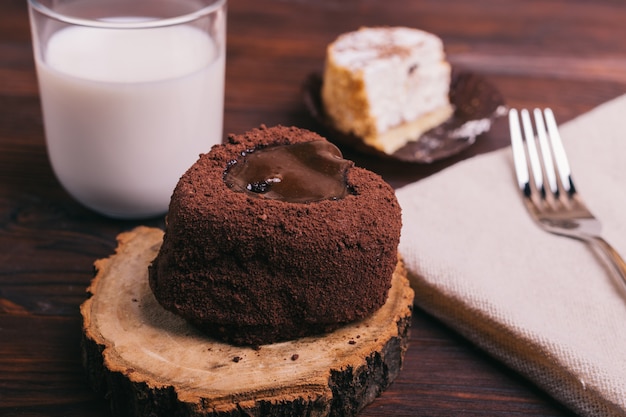 Glass of milk, cakes and fork on brown table