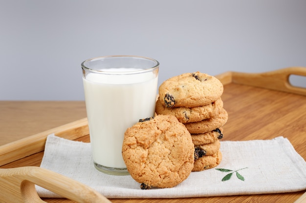 Bicchiere di latte e biscotti con uvetta su un vassoio di legno