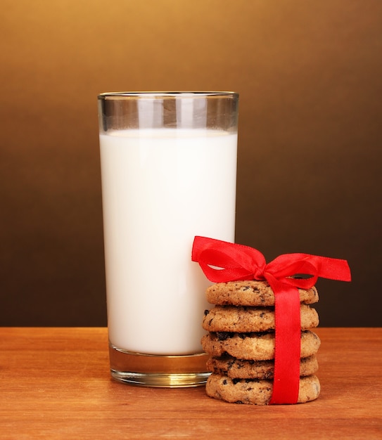 Glass of milk and cookies on wooden table