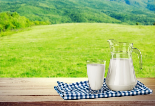 Glass of milk and jar on table with cloth and background