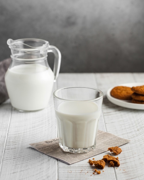 Glass of milk, jug of milk, cookies on a gray surface