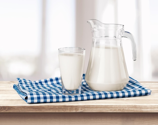 Glass of milk and jug on wooden table