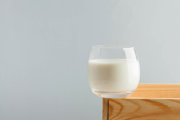 A glass of milk on a light background on a wooden box the concept of farm dairy products the use of ...