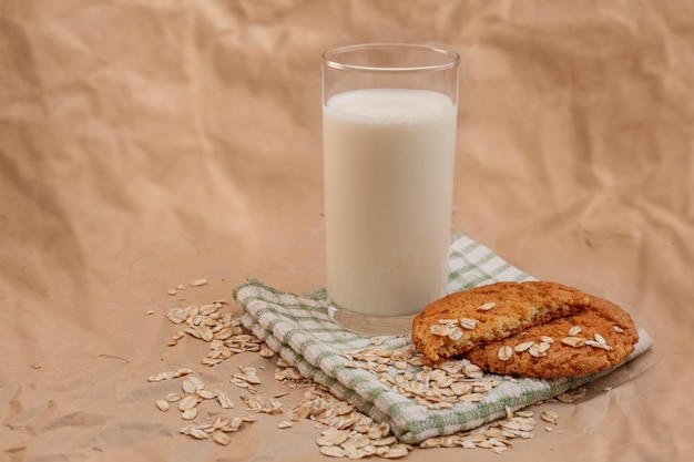 Glass of milk and oatmeal cookies on crumpled paper background