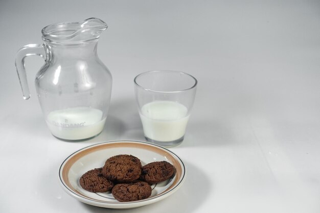 A glass of milk next to a plate of cookies and a glass of milk.