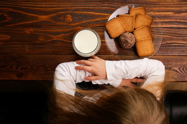 우유 한 잔과 매일 건강한 아침 식사를위한 쿠키 한 접시가 나무 테이블 위에 놓여 있습니다.