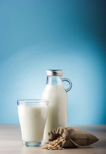 Bicchiere di latte e sacco di avena su un tavolo di legno e uno sfondo blu. cibo quotidiano