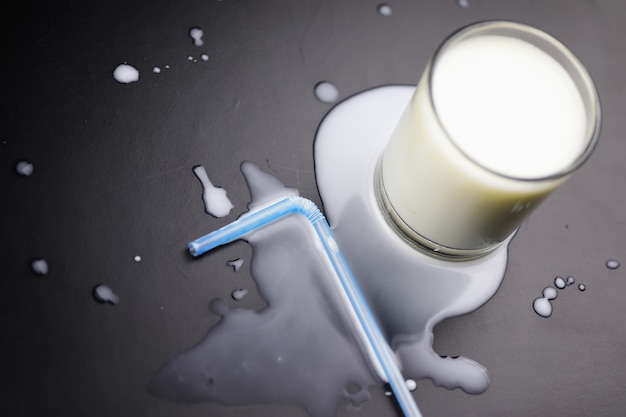 Glass of milk splashing and tube straw on the table