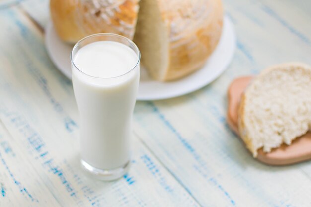 A glass of milk and white bread on a wooden background