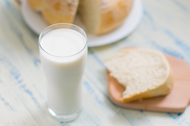 Un bicchiere di latte e pane bianco su uno sfondo di legno