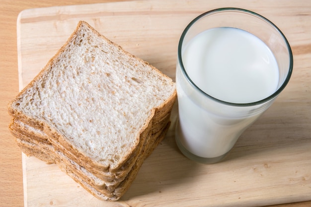 A Glass milk with bread slice on wood background