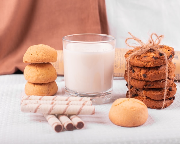 A glass of milk with caramel cookies and waffle sticks