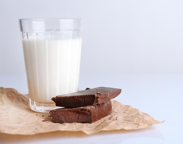 Photo glass of milk with chocolate chunks on sheet of crumpled paper isolated on white