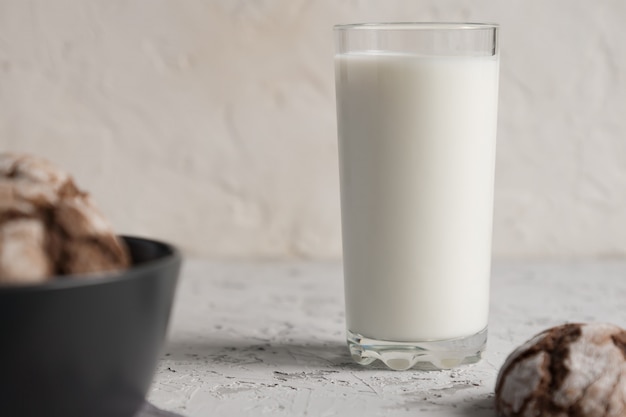 Glass of milk with chocolate cookies on a grey background.