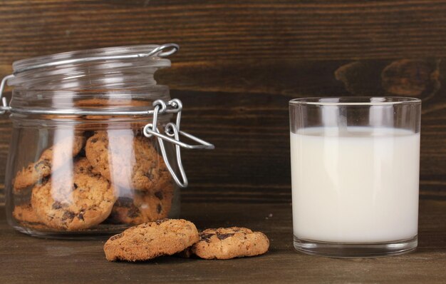 Glass of milk with cookies on wooden table closeup