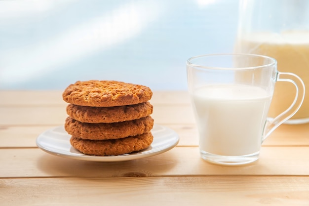 A glass of milk with cookies on a wooden table