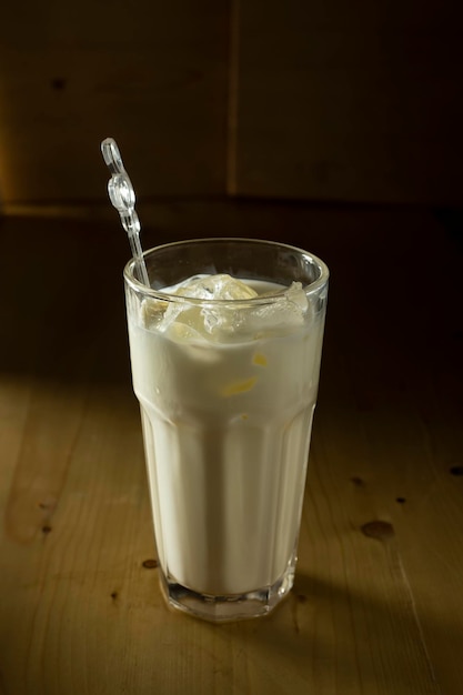 A glass of milk with ice on a wooden table