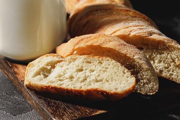 Glass of milk with sliced baguette bread on wooden board