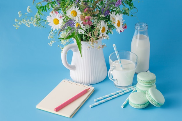 Glass of milk with striped straw sweets and macaroons