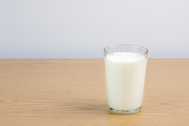 A glass of milk on a wooden table on a white background