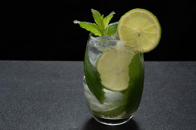 a glass of mojito cocktail on a dark background